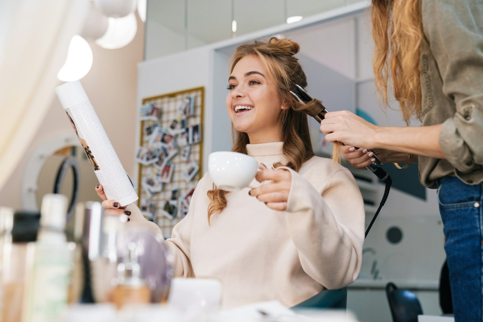 Blonde girl indoors in beauty salon with hairdresser.